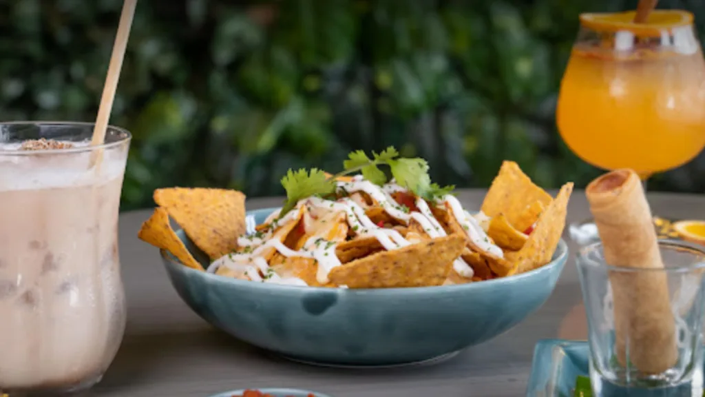 nachos served in a bowl with drink on the side.