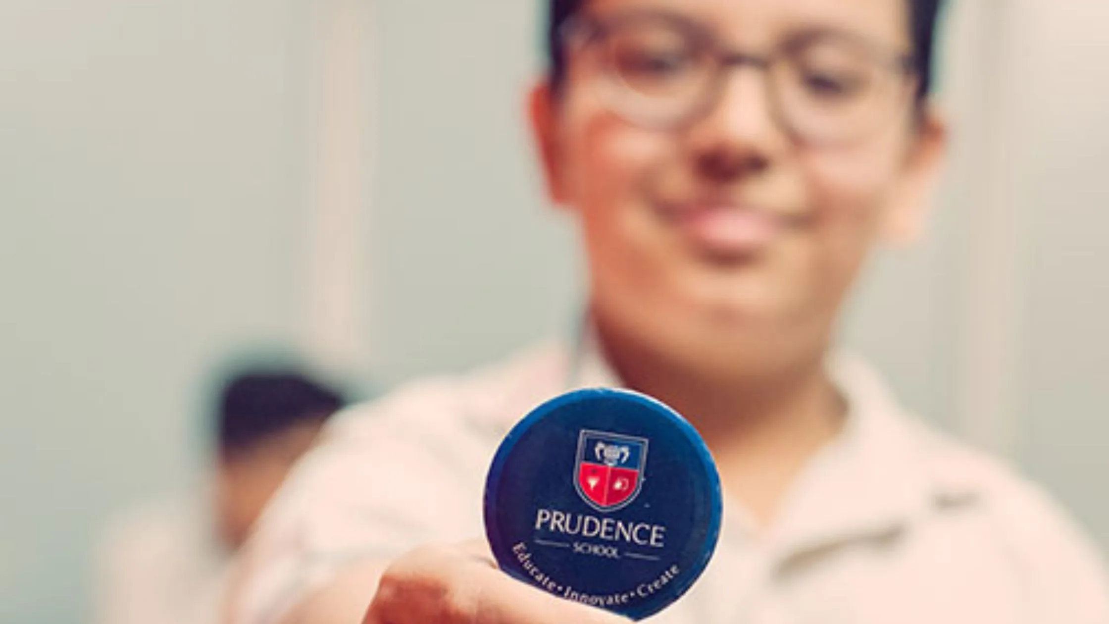 A student of Prudence School holding a badge