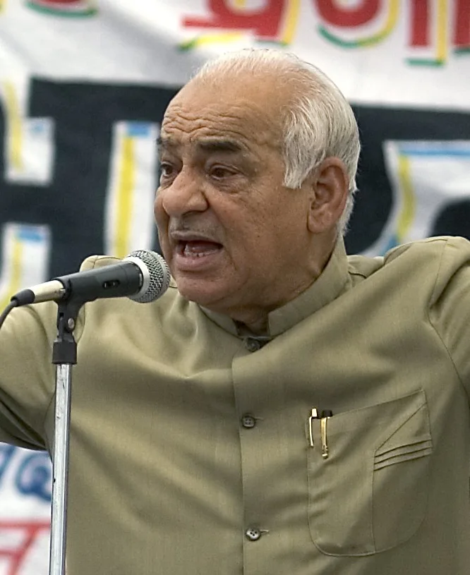 Madan Lal Khurana speaking on mic wearing Khaki colored Safari Suit.