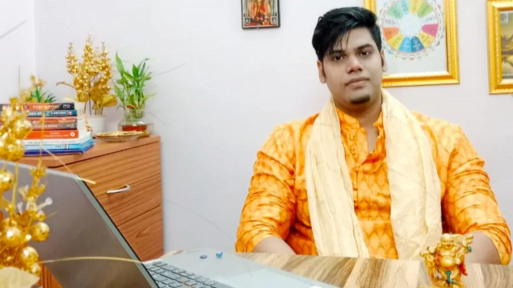 Acharya Rohan Chandra wearing yellow colored clothes sitting in his office.