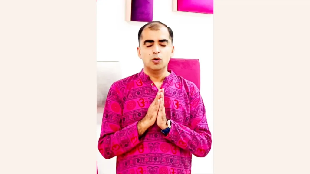 Astrologer Tanuj Lalchandani praying folding his hands. He is wearing pink colored kurta.